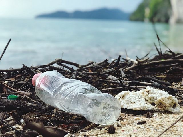 Imagen de botella de plástico en la playa con mar de forndo